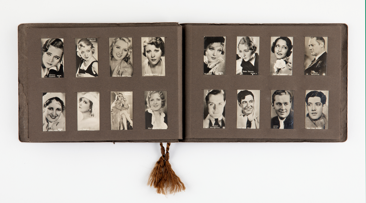 Brunt album med kartongsidor och pärmar. Varje sida har plats för 8 bilder (2,5 cm x 5 cm stora). På bilderna skådespelare, män och kvinnor. Totalt 128 bilder, alla sidor fyllda. Genom ena kortsidan trätt ett brunt tvinnat silkessnöre med en toffs nedtil.