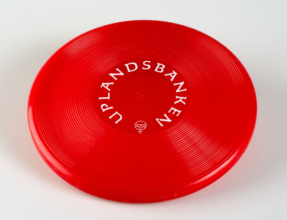 Röd plastfrisbee med Uplandsbankens logotype.