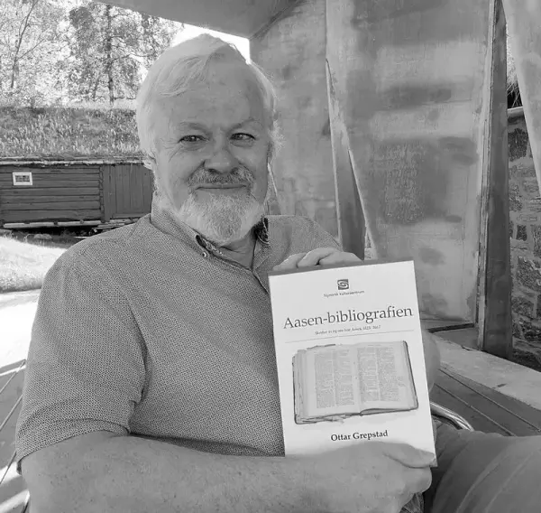 Mann viser fram ei bok