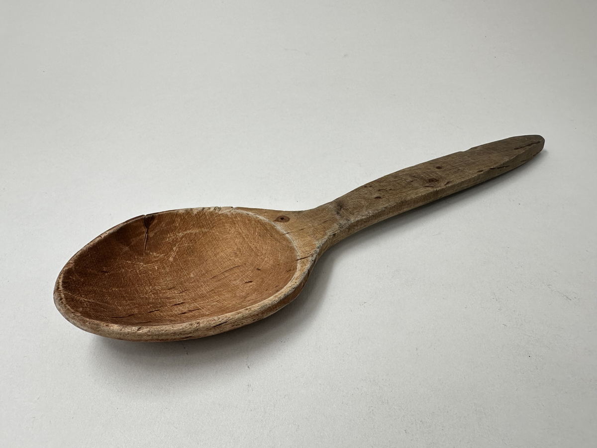 Slev av trä. Handsniden. Bruksslitage, spricka i skålen. 
