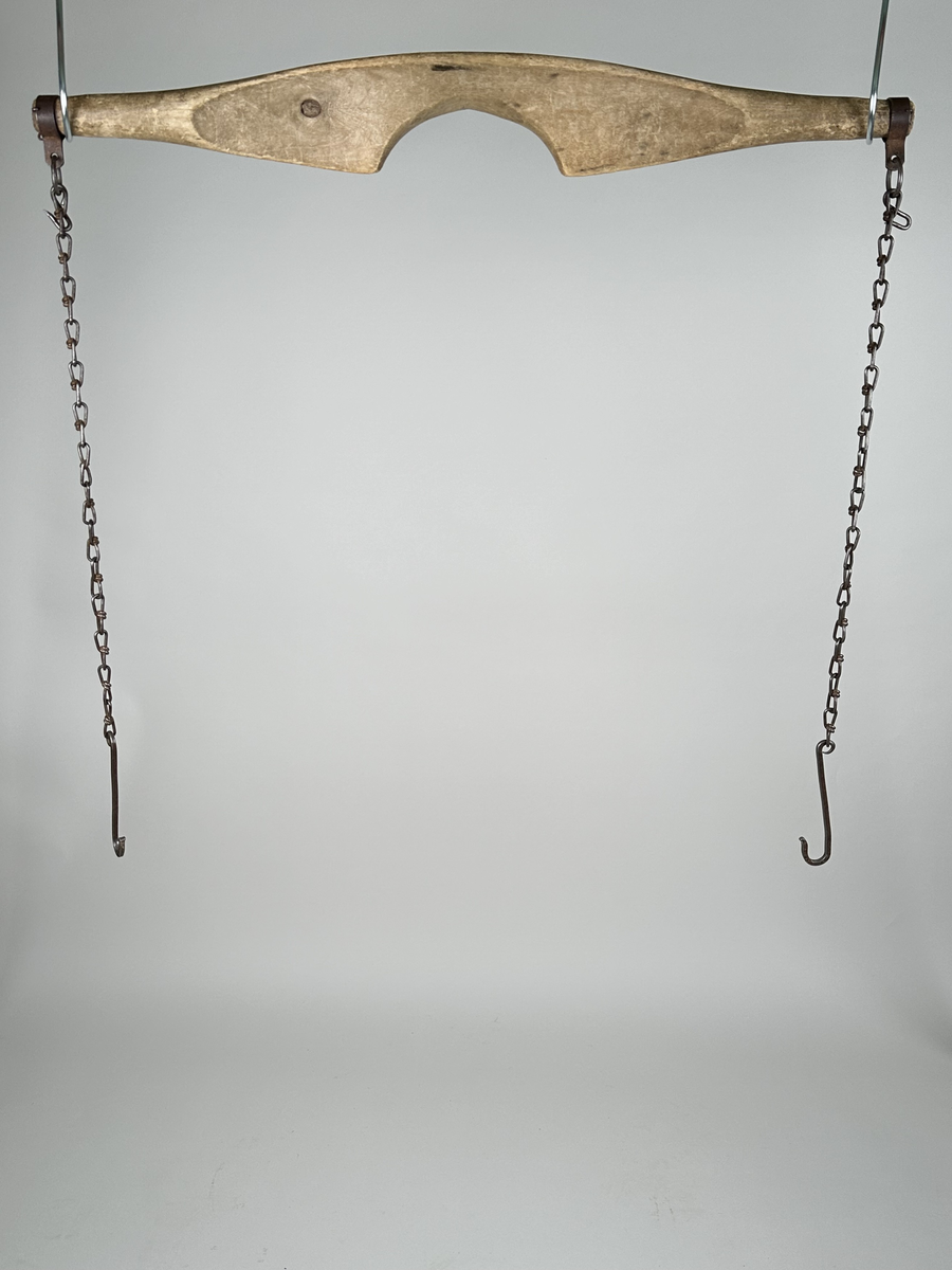 Ok, skuret av trä, troligen björk. Slätputsat, obehandlat. I varje ände sitter en ring av järn, fäst med små krampor. Från ringarna hänger kedjor, avslutade med krokar av järn. Kedjorna är maskingjorda och krokarna smidda. Det finns också krokar att fästa upp kedjorna med.
