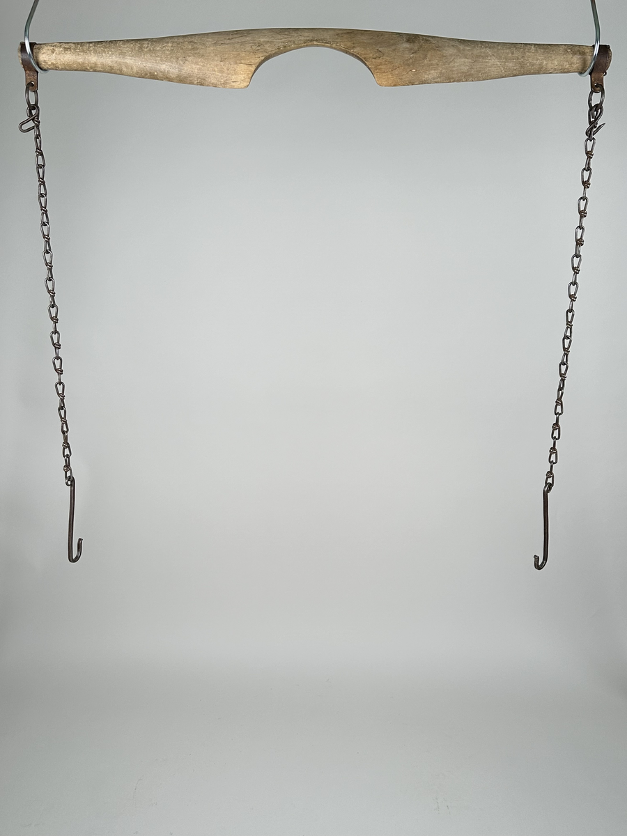 Ok, skuret av trä, troligen björk. Slätputsat, obehandlat. I varje ände sitter en ring av järn, fäst med små krampor. Från ringarna hänger kedjor, avslutade med krokar av järn. Kedjorna är maskingjorda och krokarna smidda. Det finns också krokar att fästa upp kedjorna med.
