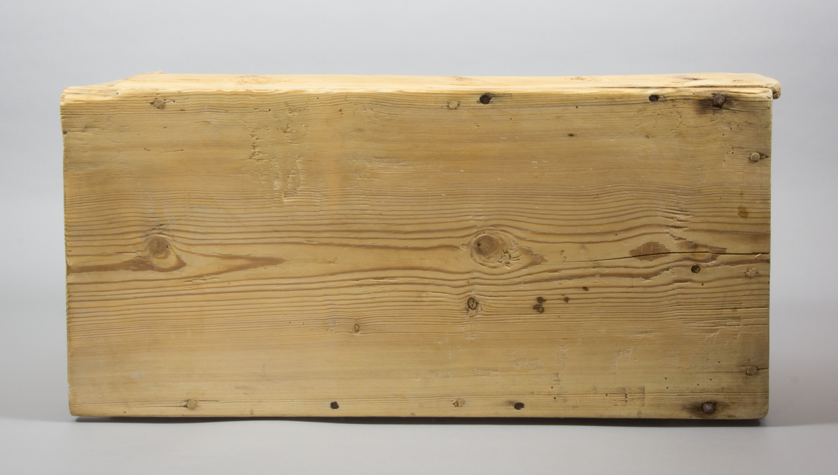 En låda tillverkad i trä. Rektangulär med raka sidor. Längst upp finns ett lock som går att fästa i en skåra i sidorna.
