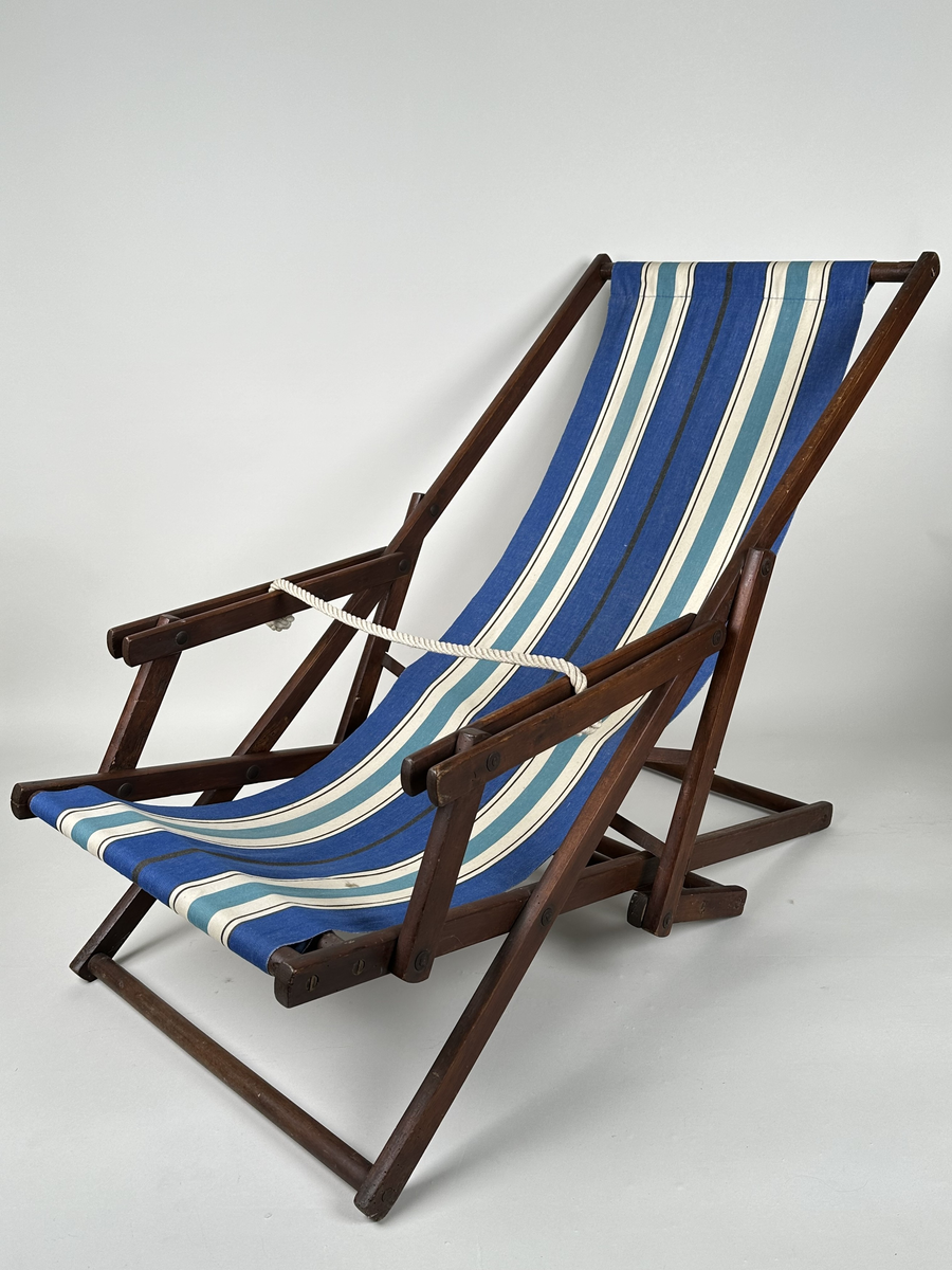 Vilstol i brunmålat trä. Sitsen i väv, långrandig i blått, vitt och svart. Justerbar rygg. Metallkryss i ryggen. 