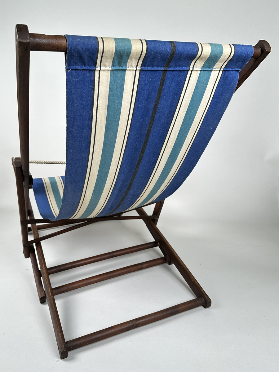 Vilstol i brunmålat trä. Sitsen i väv, långrandig i blått, vitt och svart. Justerbar rygg. Metallkryss i ryggen. 