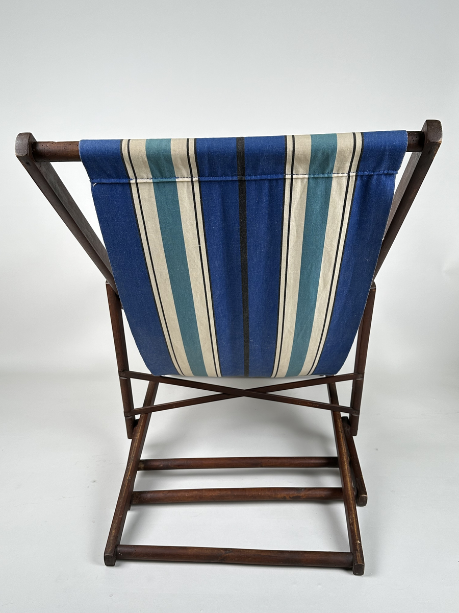 Vilstol i brunmålat trä. Sitsen i väv, långrandig i blått, vitt och svart. Justerbar rygg. Metallkryss i ryggen. 