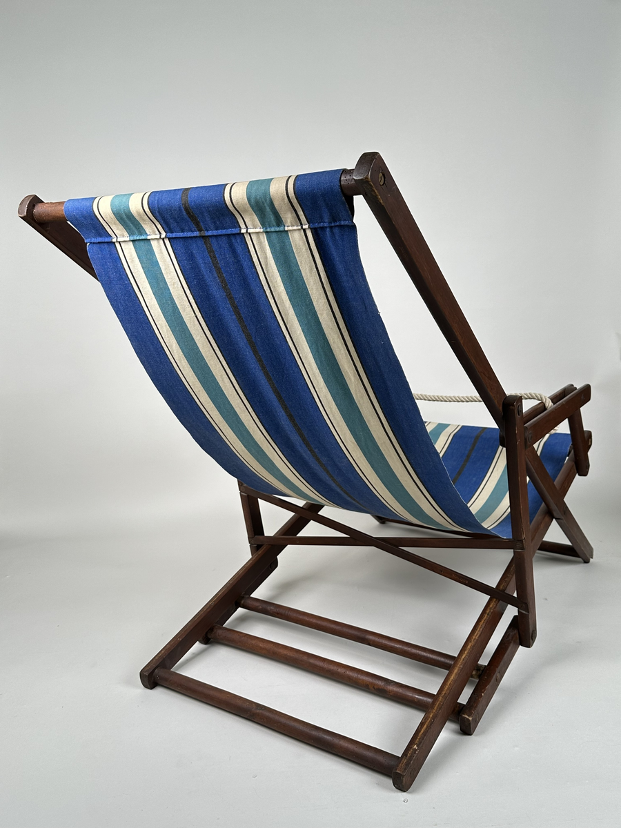 Vilstol i brunmålat trä. Sitsen i väv, långrandig i blått, vitt och svart. Justerbar rygg. Metallkryss i ryggen. 