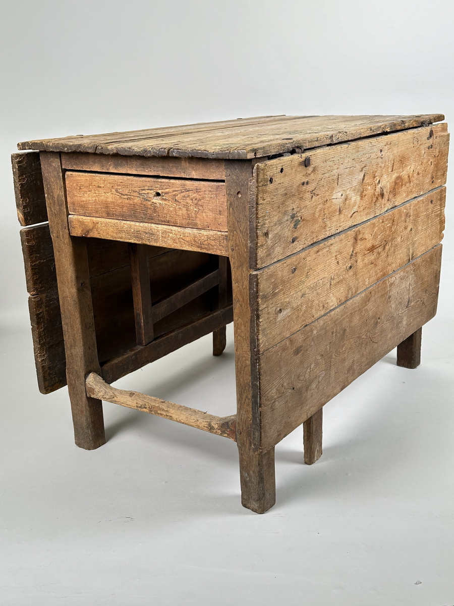 Slagbord i furu. Bordstativ vari två utfällbara stöd för klaffarna fälls ut. Bordskiva samt klaffar av breda plankor. Lådor i sargen på sidorna utan klaffar. 