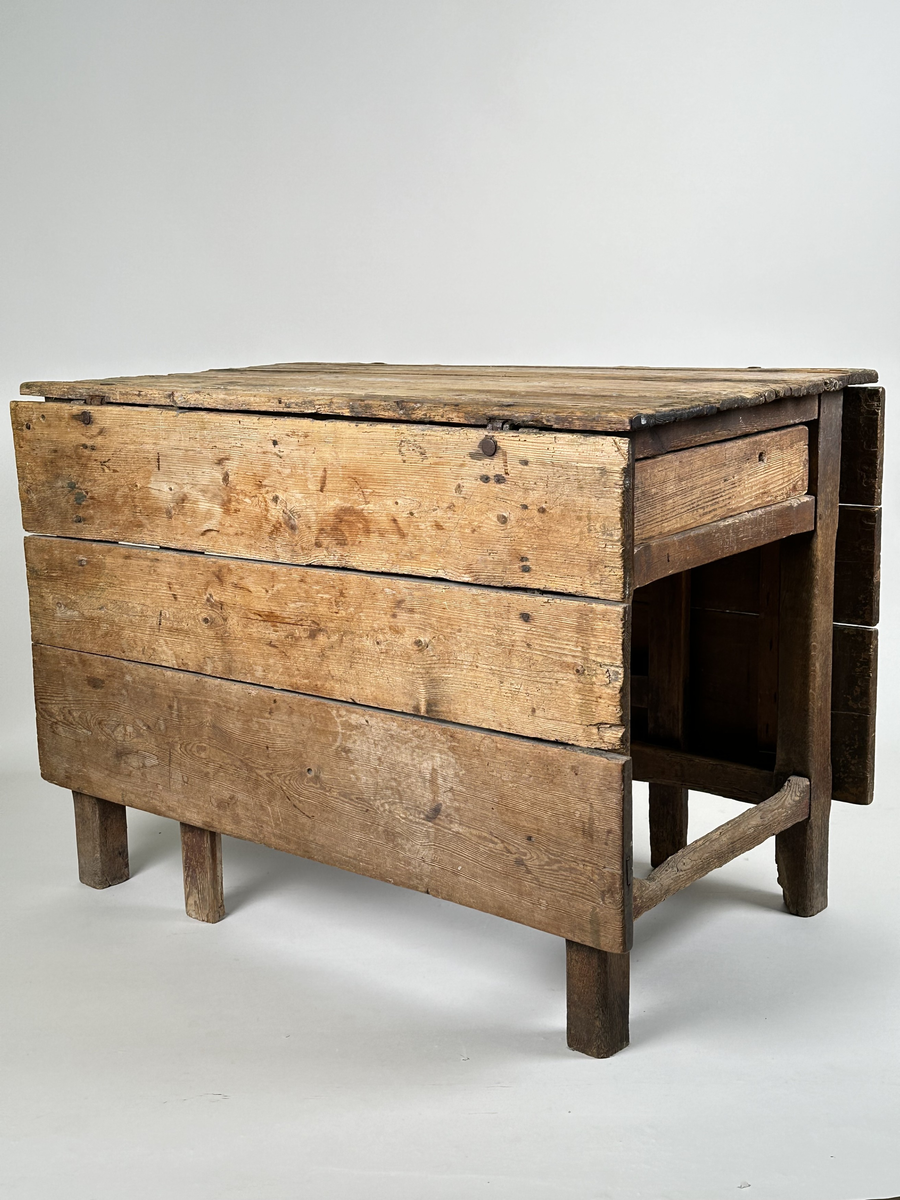 Slagbord i furu. Bordstativ vari två utfällbara stöd för klaffarna fälls ut. Bordskiva samt klaffar av breda plankor. Lådor i sargen på sidorna utan klaffar. 