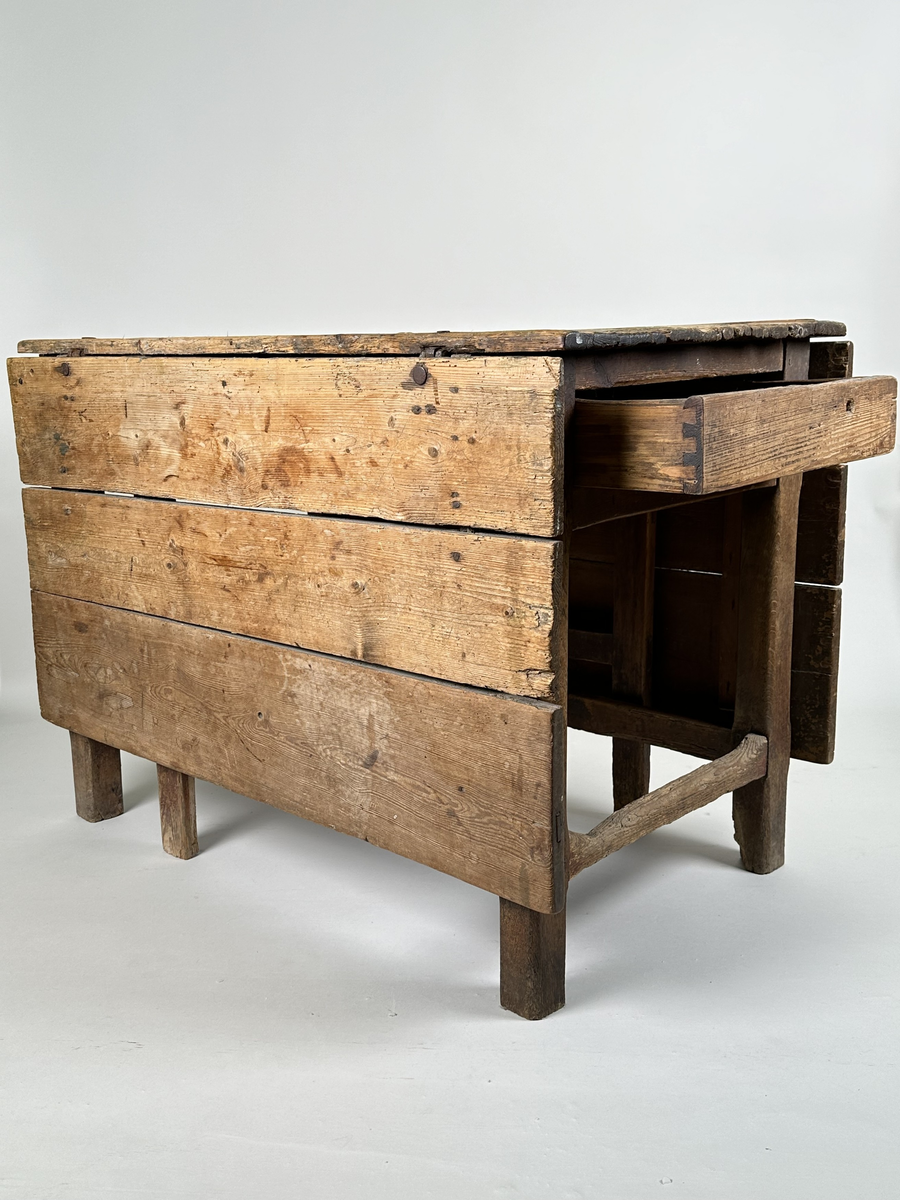 Slagbord i furu. Bordstativ vari två utfällbara stöd för klaffarna fälls ut. Bordskiva samt klaffar av breda plankor. Lådor i sargen på sidorna utan klaffar. 
