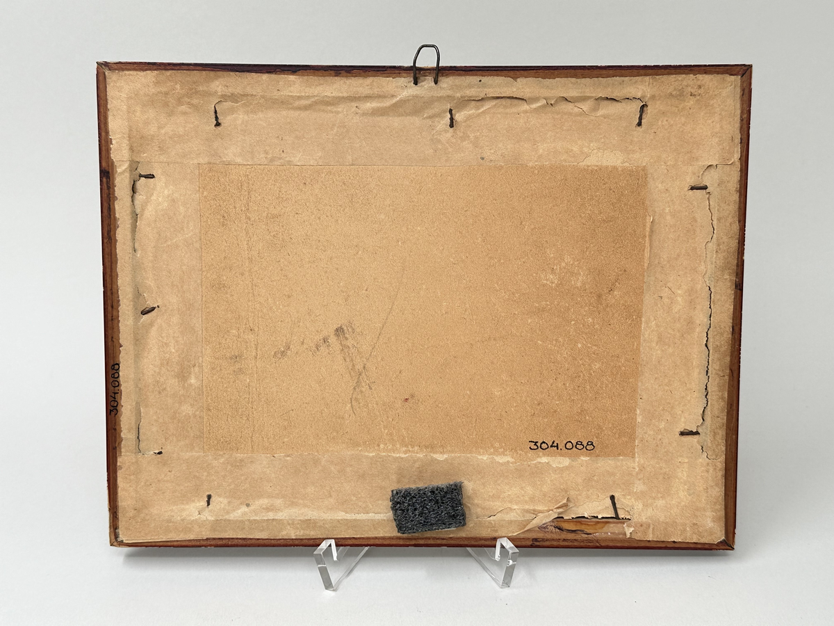 Fotografi i ram. Svartvitt fotografi föreställande Per Åkesson tillsammans med en av hans söner hållandes i varsin häst, Fux och Stjärna, framför gården Hög 18:1. Runt fotografiet passepartout av beige kartong. Ramen ådringsmålad i brunt, med glasfront och baksida av kartong som är fäst med stift och förseglat med klisterremsa. Hängare av en tunn märla av ståltråd.