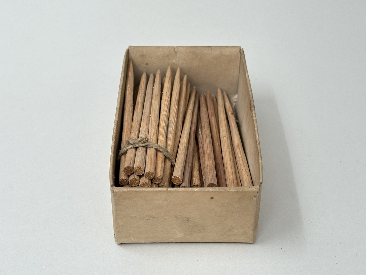 75 handtäljda stickor av furu. Oanvända. Liggandes i öppen ask av naturfärgad papp.