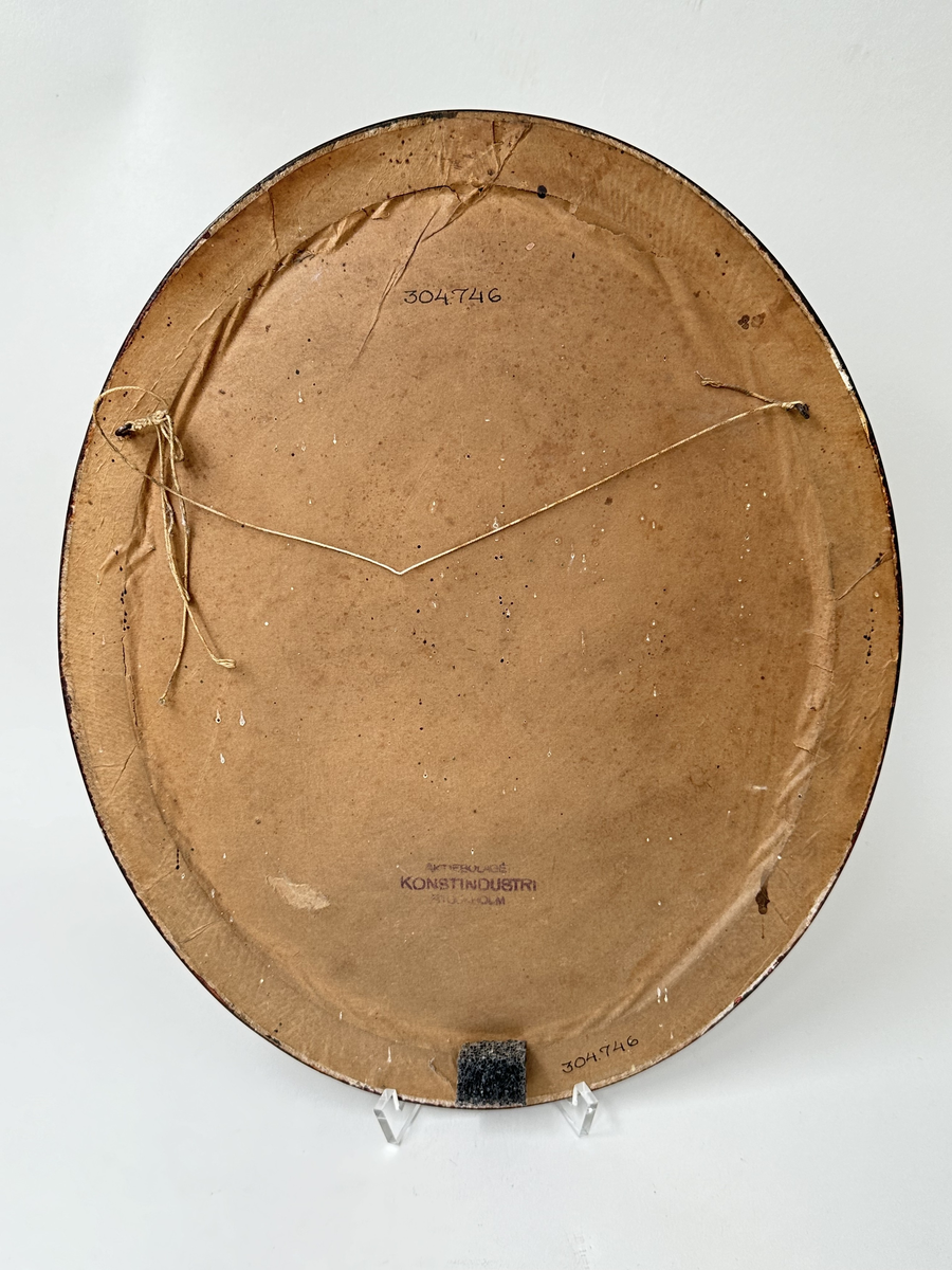 Fotografi i ram. Svart-vit bröstbild av man i skärmmössa och kavaj. Glas och brun träram. Ovalt format. 