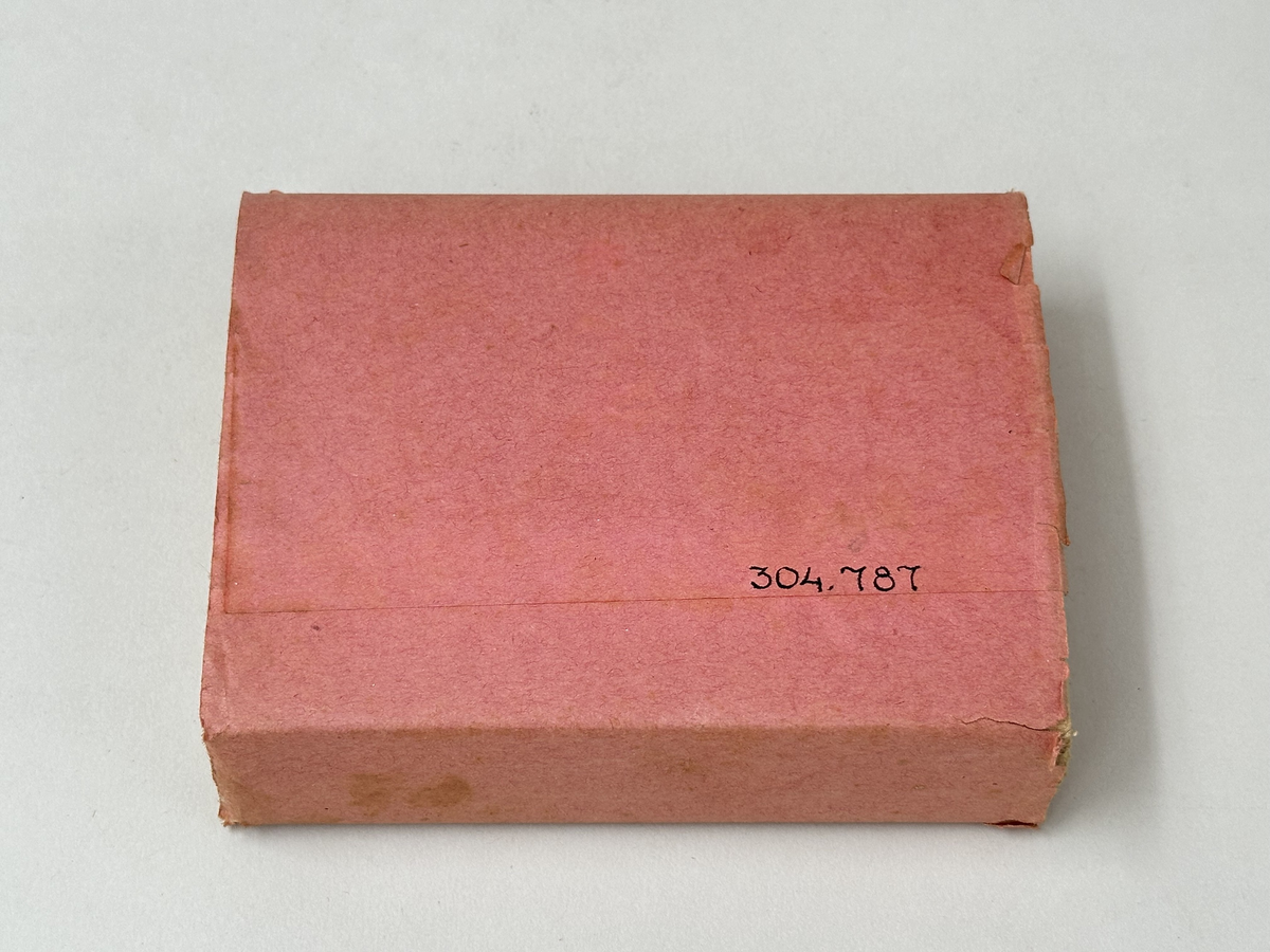 Toalettpapper, en bunt ark i rosa pappersomslag med tryckt mörkblå text och cirkel med ett kors i.