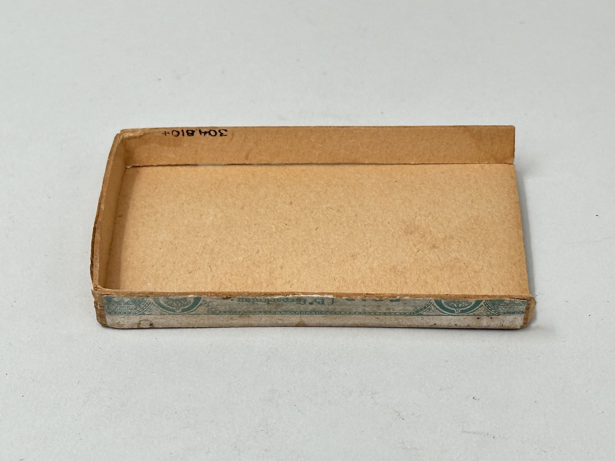 Lock till ask, av hårdpapp som utvändigt klätts i trämönstrat papper. På locket, gul etikett med grönt tryck: "Havanna no 2, no 204 AB Svenska Tobaksmonopolet".