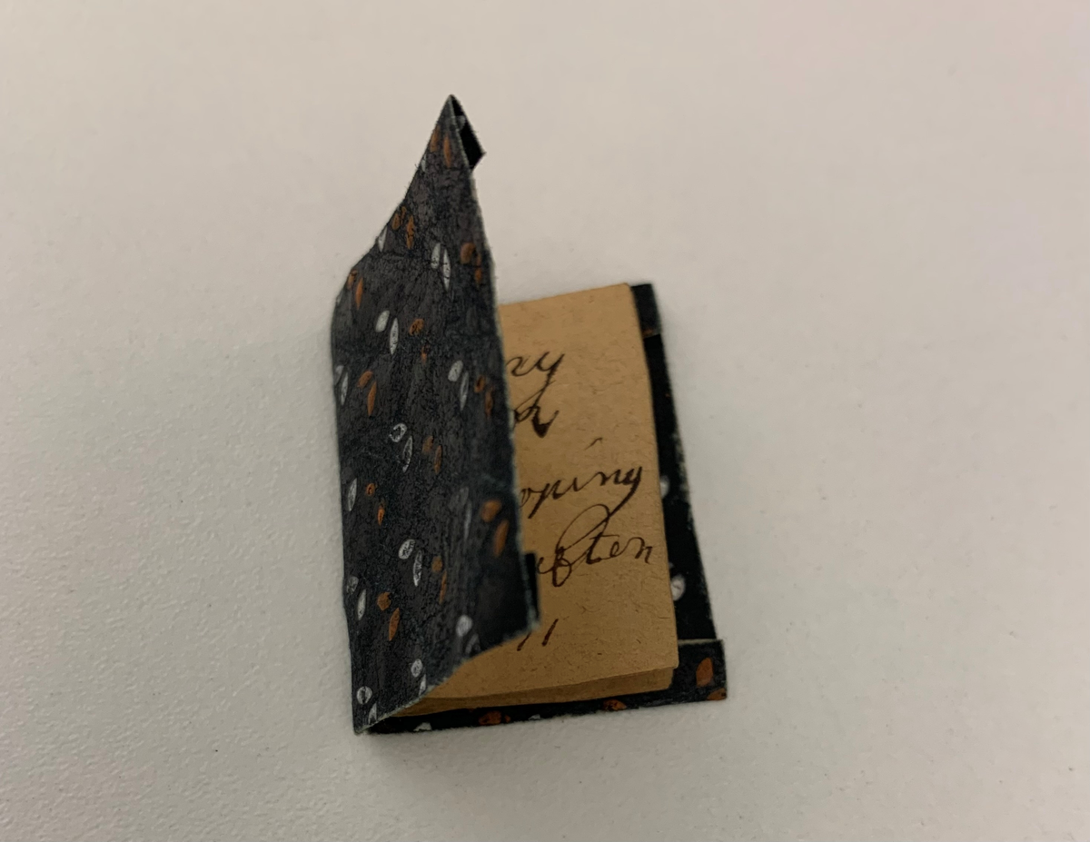 Skrivbord av brunmålat trä med guldfärgade dekorationer. Överdelen har två skåp med hyllor emellan. Under skrivbordsskivan finns fem lådor. På tre av lådorna har lådfronten lossnat. Vid uppackningen i Morgongåva förvarades i skrivbordet följande saker: fyra snäckor, en kortlek, en sten, en glasbit, en bägare (av ben?). Nummer UM 8384 d har också ett häfte med namn och årtal i. Häftet är 3,5x3 cm.