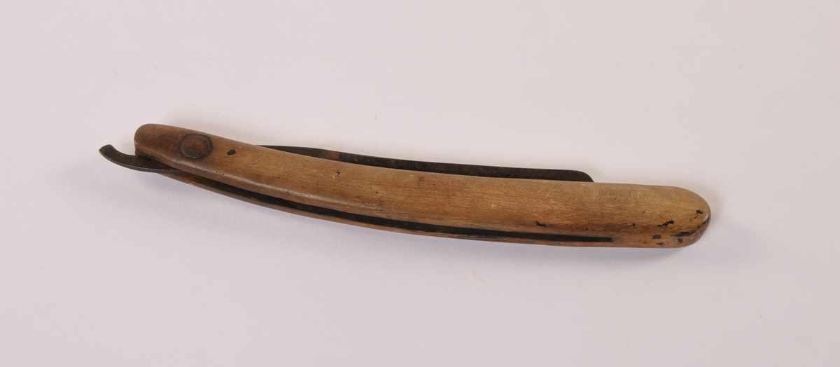 Barberkniv med jernblad til å felle inn i buet treskaft.