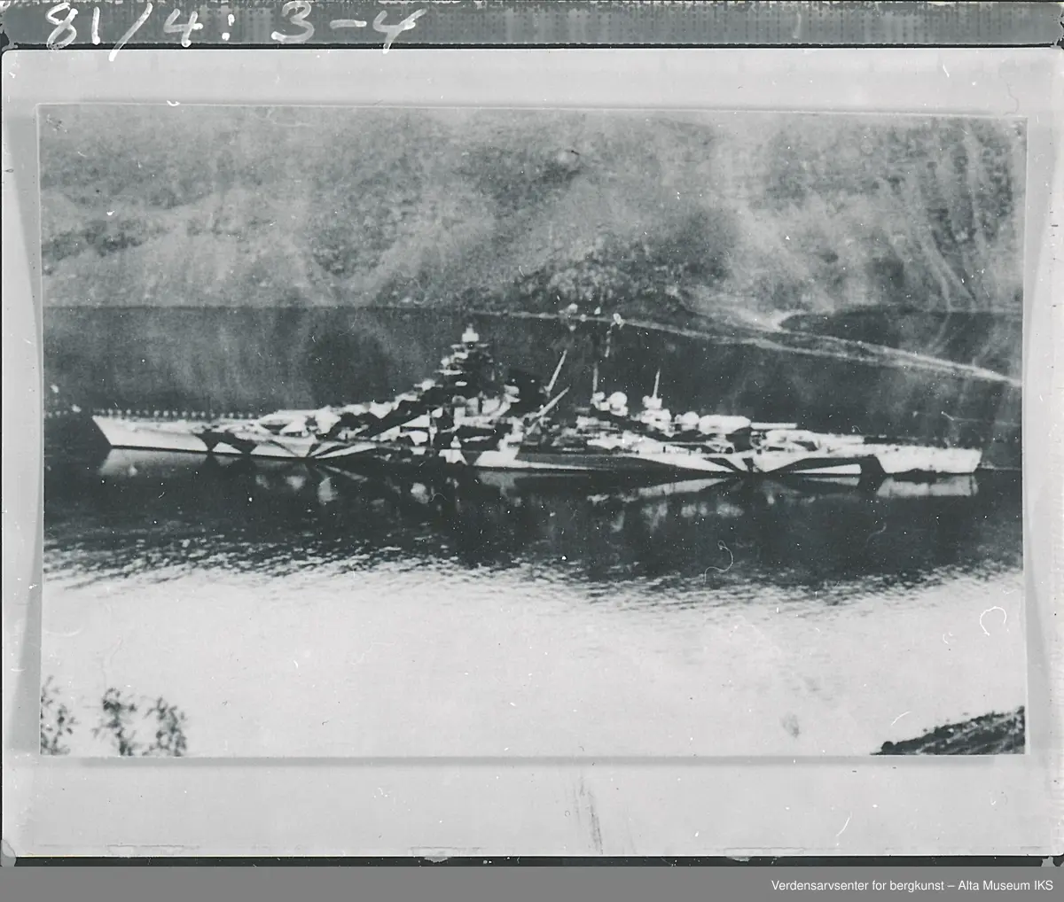 Tirpitz fortøyd i Kåfjord 1943. Foto viser hele skipet fra baug til akter, ikledd kamuflasje dekor. Sett fra skipets babord side. 