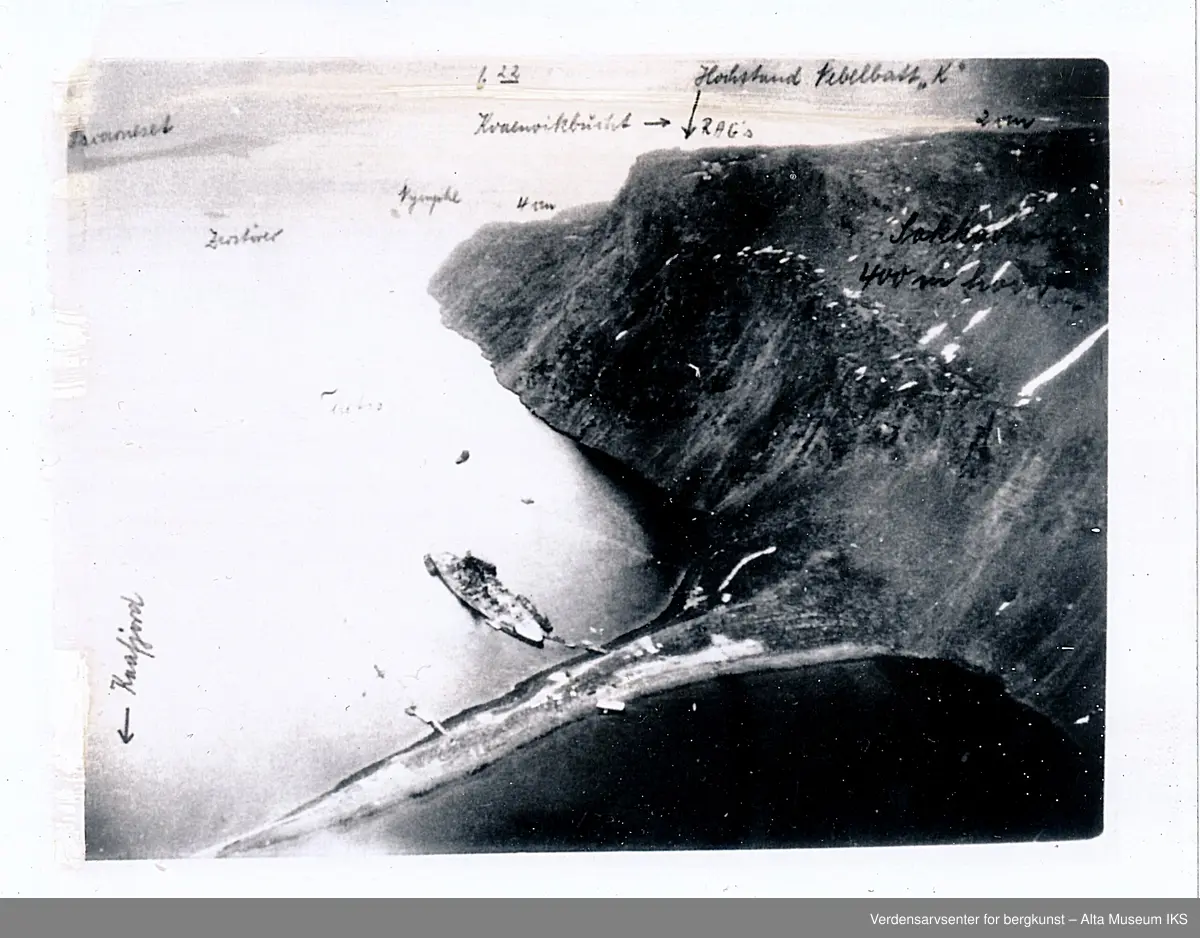 Tirpitz, slagskip og søsterskip til Bismarck fortøyd i Kåfjord, Alta Kommune i 1943. Bildet er tatt ovenfra i fly. Skipet ligger fortøyd der Kåfjord- brua og utløpet til tunnelen er i dag. På bildet er det også skrevet opp navn på båter. Batteriet på Sakkobane kan sees.