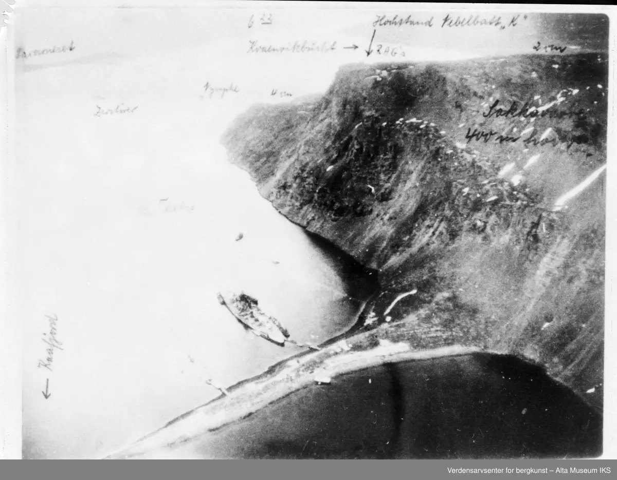 Tirpitz, slagskip og søsterskip til Bismarck fortøyd i Kåfjord, Alta Kommune i 1943. Bildet er tatt ovenfra i fly. Skipet ligger fortøyd der Kåfjord- brua og utløpet til tunnelen er i dag. På bildet er det også skrevet opp navn på båter. Batteriet på Sakkobane kan sees.