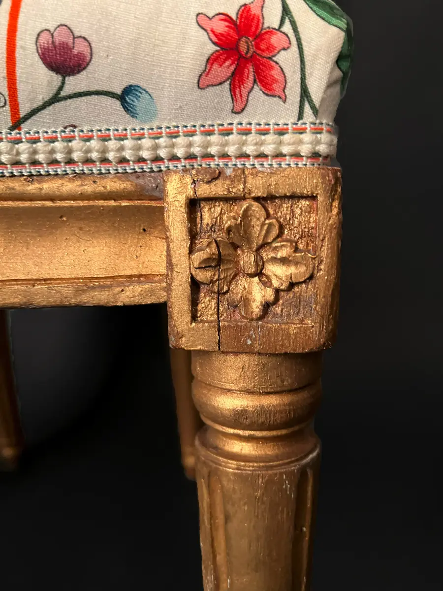 Ett par stolar i gustaviansk stil. Raka, räfflade och neråt avsmalnande ben. Sargen är rak och prydd med hörnrosetter ovanför benen. Framsargen har en blomdekor i mitten. Ryggen har en oval form och är krönt med en snidad ros. Ryggens mitt samt stolens sits är stoppade och klädda i ett vitt tyg med blomsterdekor i grönt, rött och blått. Stolens stomme är förgylld. Ursprungligen har stolen varit klädd i svart läder och ryggens baksida med rött tyg.