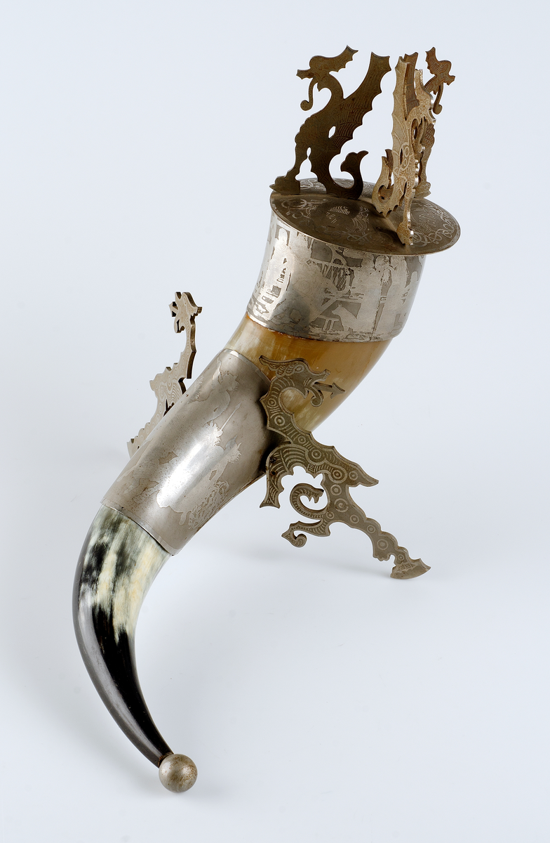 Gulvitt horn med beslag och lock av silverimiterande metall. På lockets översida runor och slingor i fornnordisk drakstil. På lockets undersida ingraverat: Jag kom i arf till en skolgosse i Sept 1861. Kom med en student till Akad 18 13/9 74: bofästes och invigdes 18 13/9 81 och har under dessa 20 år likväl ej ombytt ägare. 
På beslagen "vikingascener".
 
