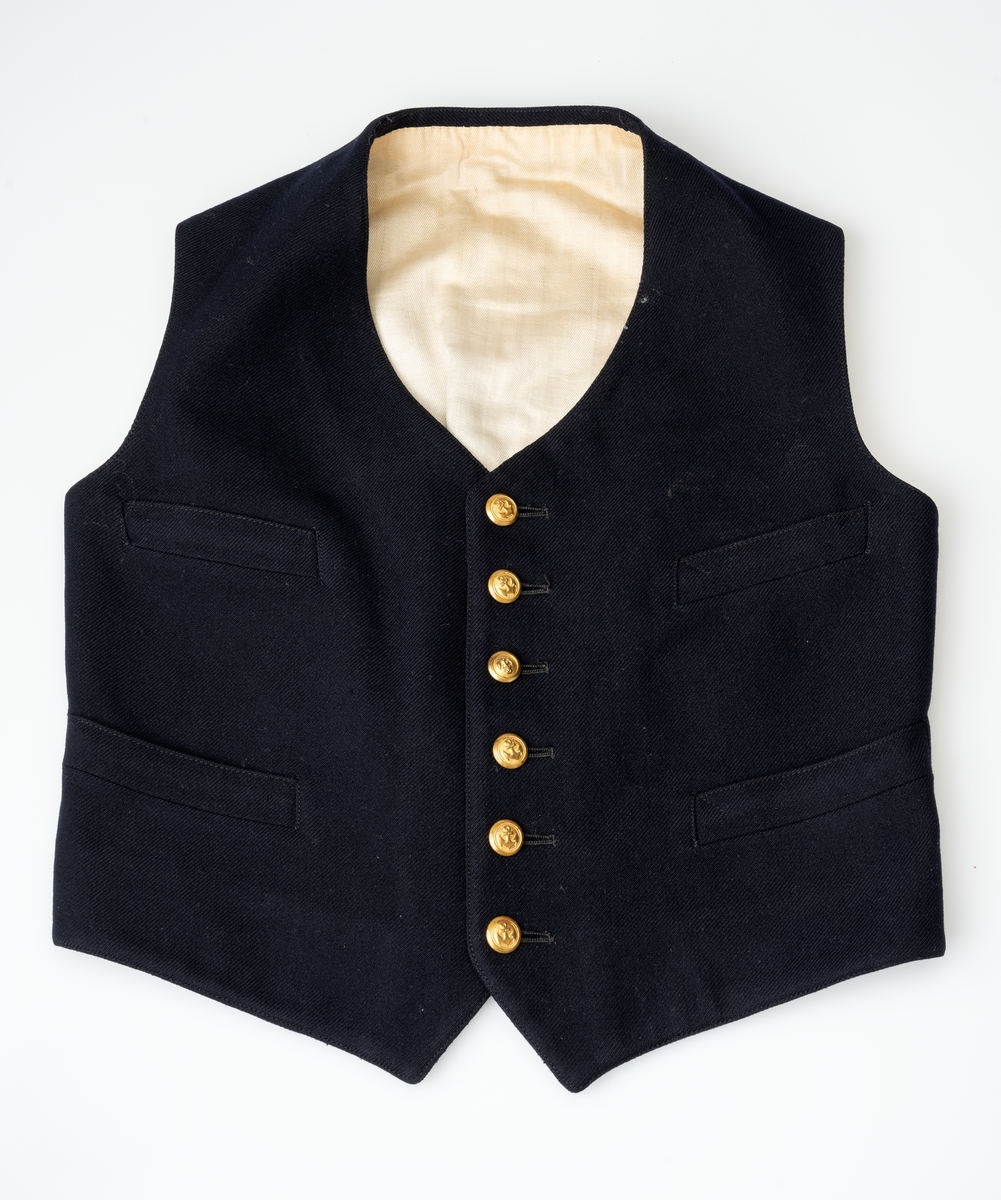 Matrossdress jakke og vest: Dobbelspent, mørkeblå matrosjakke i ull m. seks gullknapper og seks knappehull i hver side. En knapp og et knappehull på hvert jakkeslag. Distinksjoner på ermene:  tre striper med påsydde smale gullbånd. Seks mindre knapper nederst på ermene. Skråsydd ned midt foran og midt bak. Kort modell. Sort forstoff innvendig, hvit forstoff i ermene. Hempe i nakken, liten innerlomme i høyre side m. maskinsydd monogram. Anker på knappene.
Mørkeblå matrosvest i ull m. seks gullknapper i front og to lommer i hver side. Bakstykke i sort blankt stoff m. belte og spenne, liten splitt MB. Hvitt forstoff invendig.