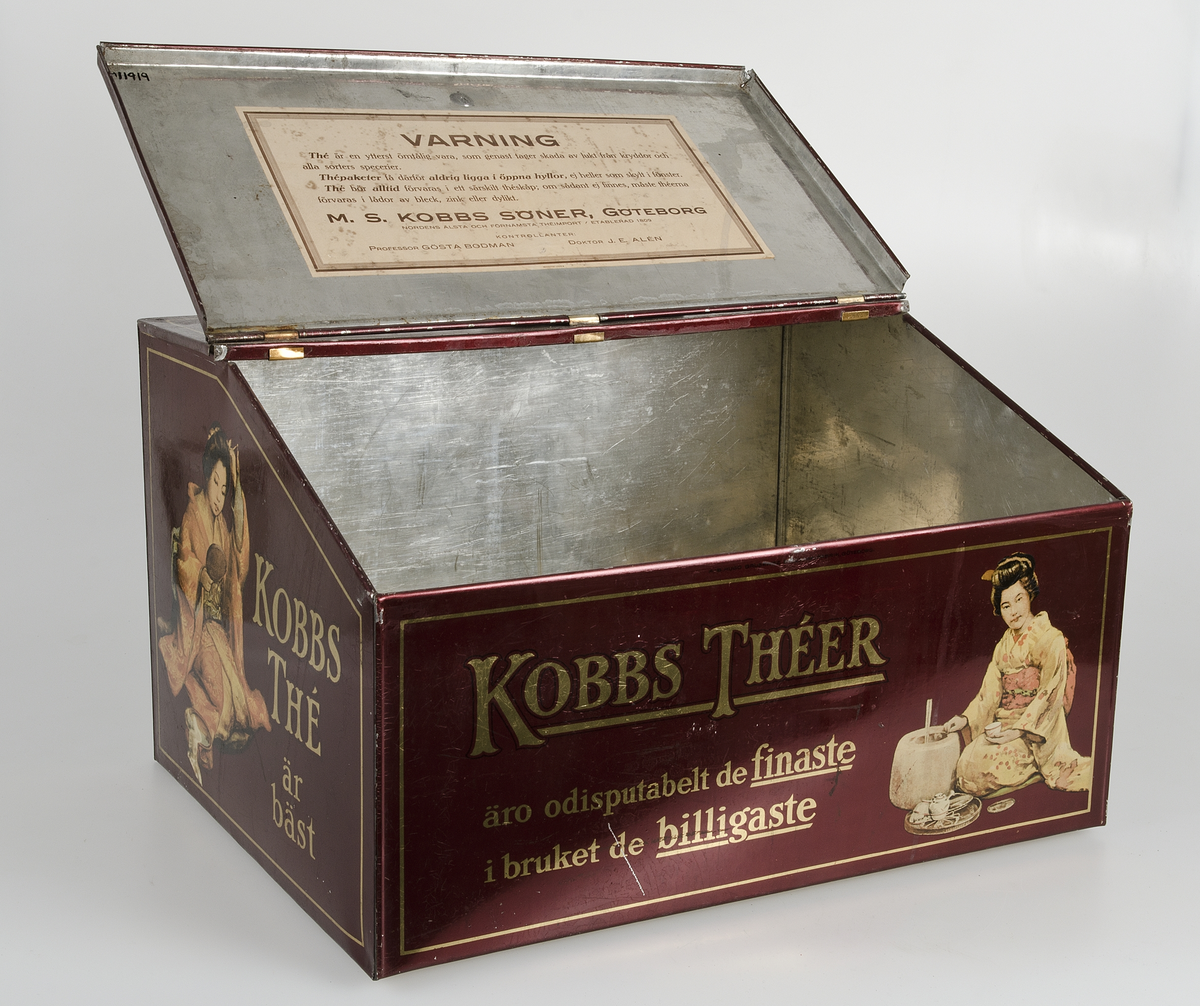 Mörkröd med text i guld "M. S. Kobbs söner Göteborg, Nordens äldsta och förnämsta theimport. Etablerad 1809, kontrollant Doktor J. E. Alén". På fram- och baksida "Kobbs theér äro odiskutabelt de finaste i bruket de billigaste". På kortsidorna "kobbs thé är bäst". Polykrom dekor. Lockets insida har en påklistrad ljusbrun pappersetikett med brun text med råd om förvaring av té.
 
