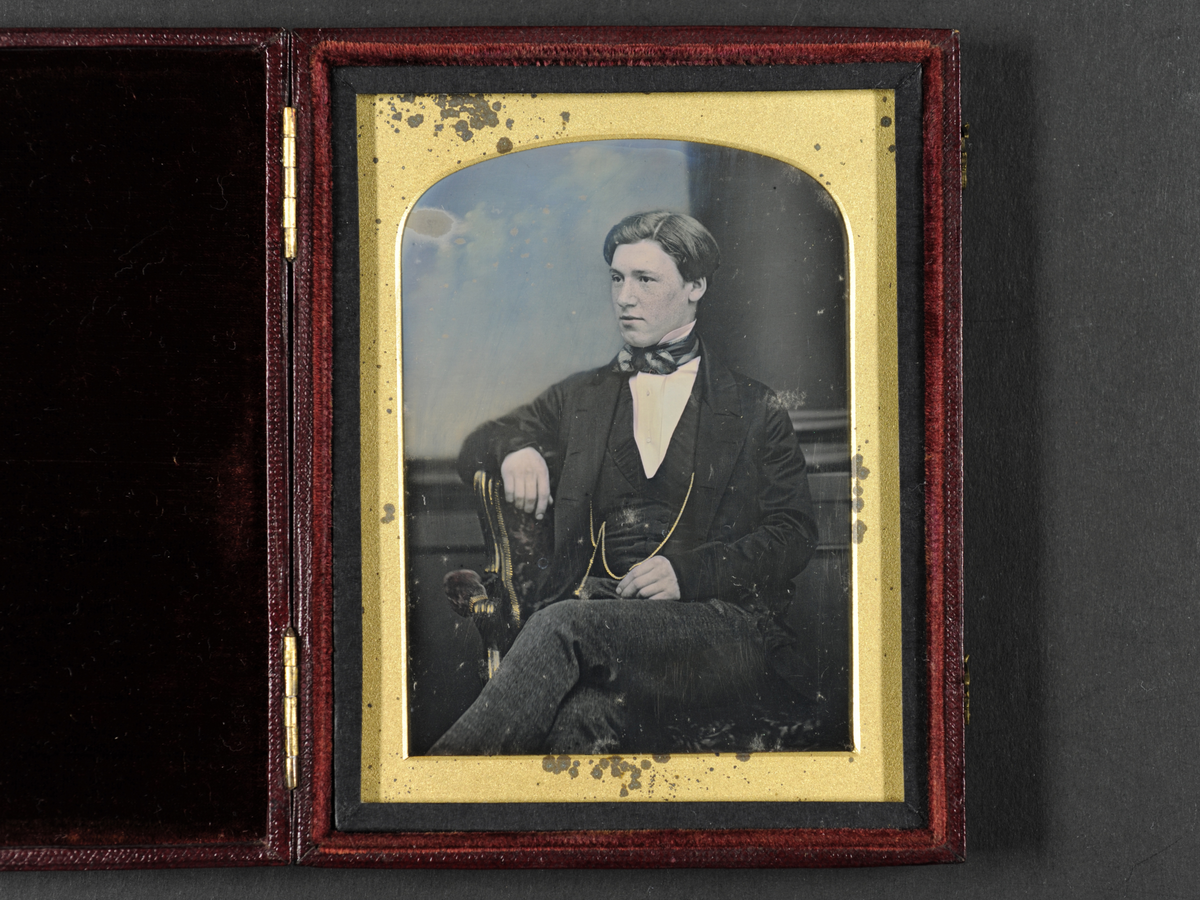 Daguerreotypi: Portrett av sittende ung mann, 3/4 profil. Håndkolorert.