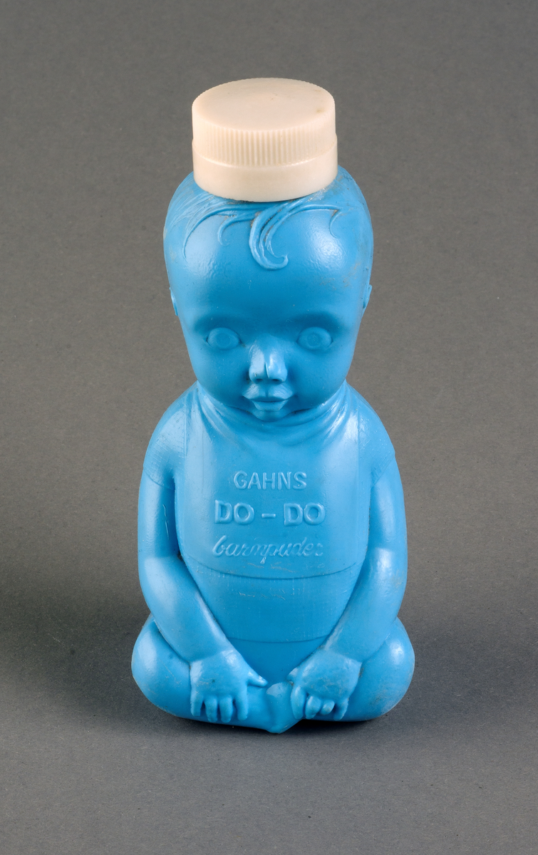 Förpackning av ljusblå hårdplast i form av en sittande baby med tröja och haklapp. Text i relief: GAHNS DO-DO BARNPUDER. Skruvlock av vit hårdplast. I botten text: SV. AB POLVA.