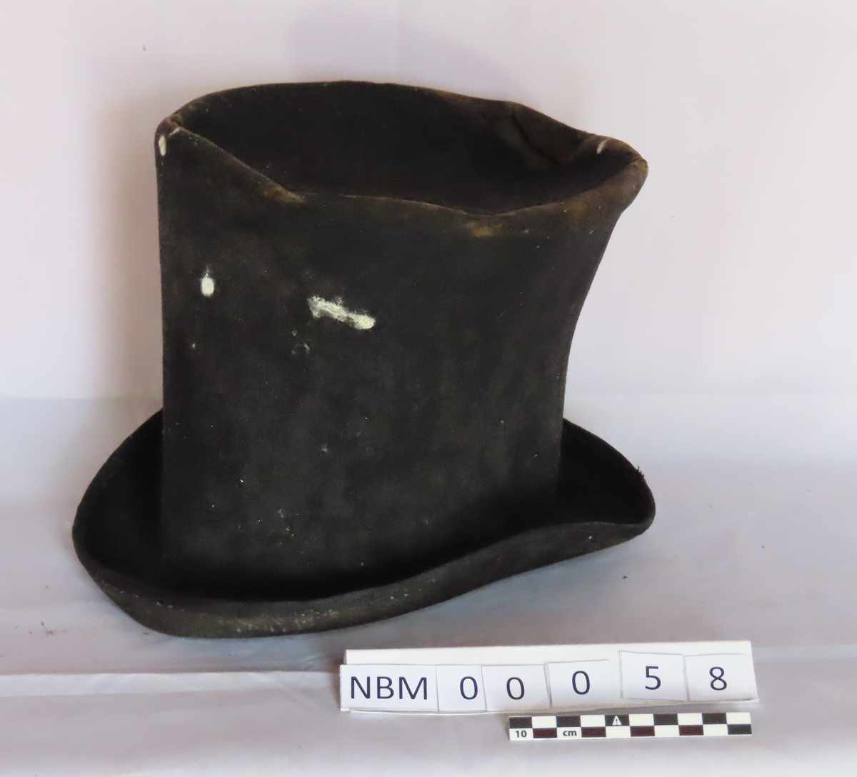 Hatt med brem kantet med svart bånd. Stikninger mellom pull og brem.