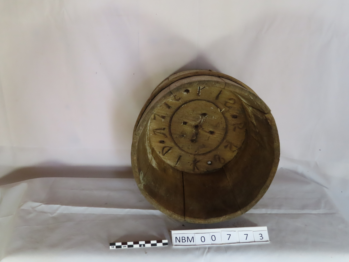 Form: Stavform med trett. Utgående rør fra hovedrør. Streng med lodd gjennom røret.