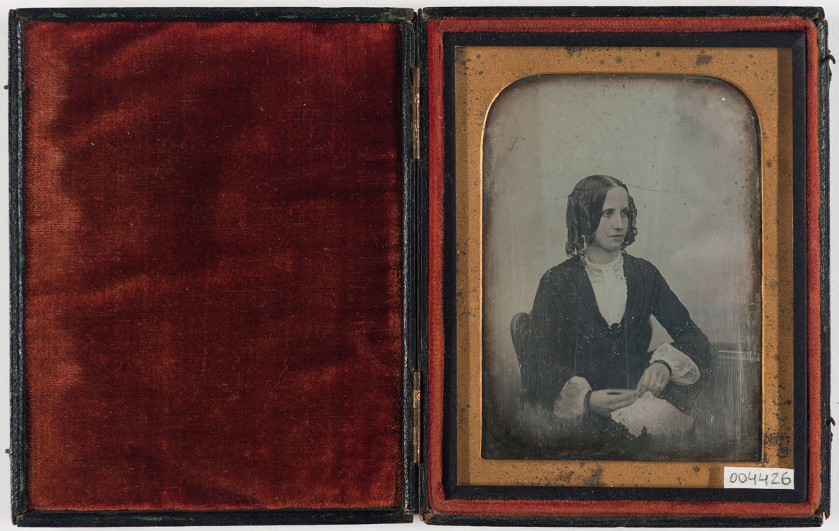 Daguerreotypi: Portrett av en sittende kvinne med krøller, halvfigur.