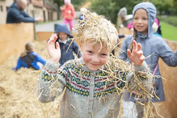 En gutt og en jente leker i halmen. 