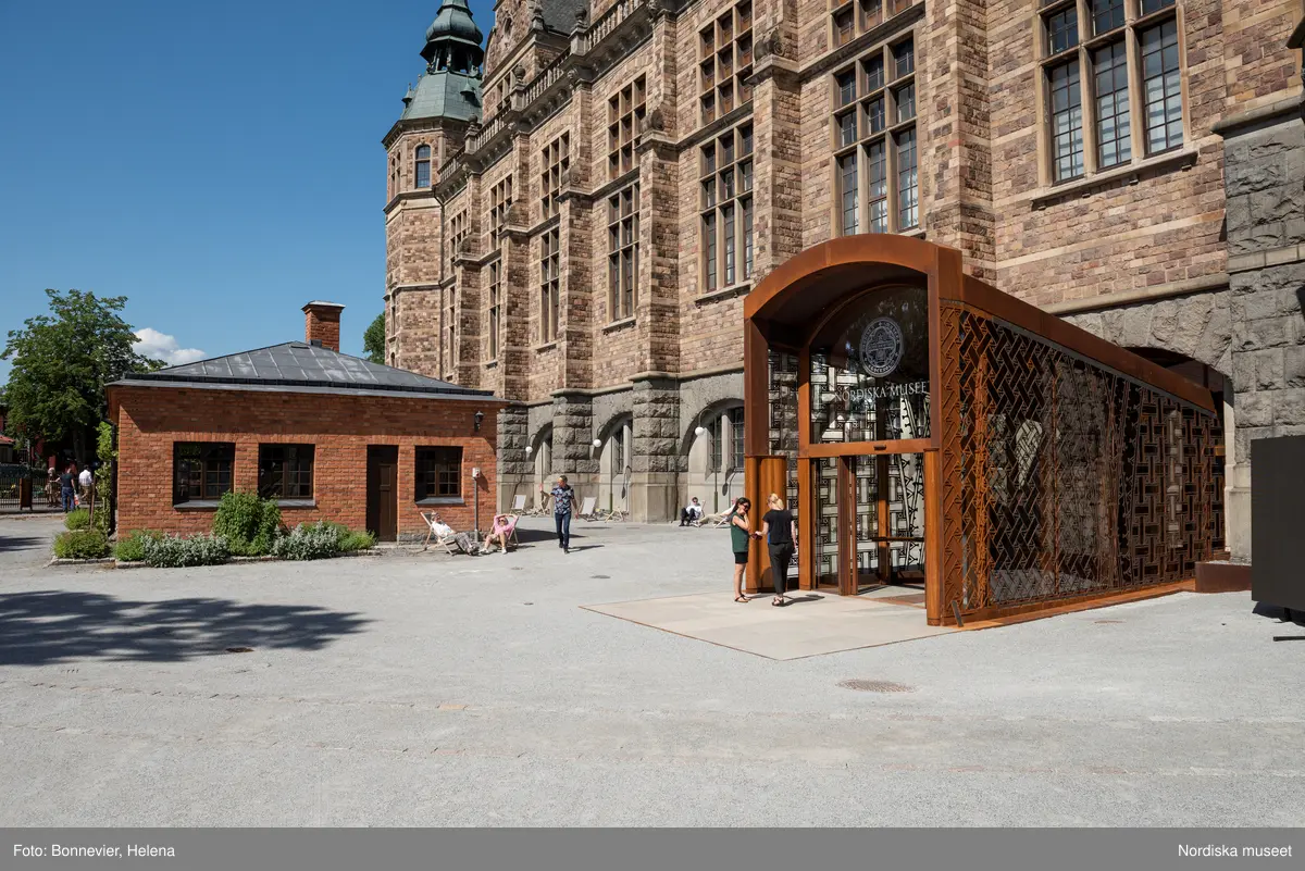 Exteriörer från Nordiska museets västra sida, bakgården, med den nya entrén och byggnaden Lusknäppen. Entrén är ritad av Lone-Pia Bach. Konstnären Outi Pieski står för den konstnärliga gestaltningen med konstverket Two Directions, inspirerat av föremål ur museets samiska samlingar.