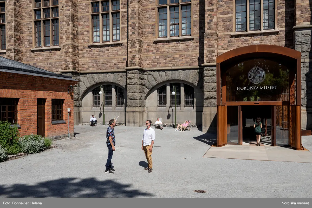 Exteriörer från Nordiska museets västra sida, bakgården, med den nya entrén och byggnaden Lusknäppen. Entrén är ritad av Lone-Pia Bach. Konstnären Outi Pieski står för den konstnärliga gestaltningen med konstverket Two Directions, inspirerat av föremål ur museets samiska samlingar.