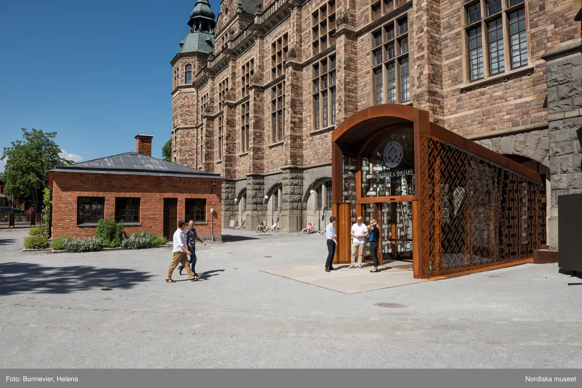 Exteriörer från Nordiska museets västra sida, bakgården, med den nya entrén och byggnaden Lusknäppen. Entrén är ritad av Lone-Pia Bach. Konstnären Outi Pieski står för den konstnärliga gestaltningen med konstverket Two Directions, inspirerat av föremål ur museets samiska samlingar.