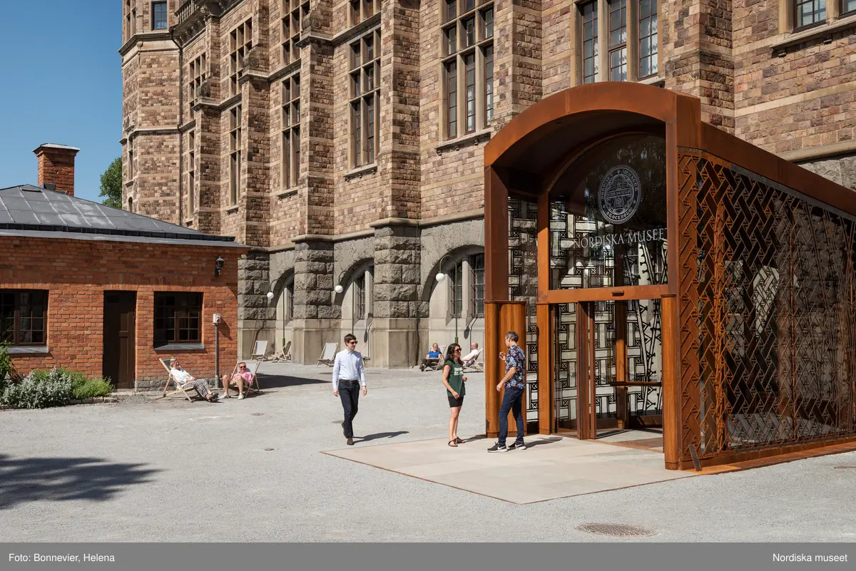 Exteriörer från Nordiska museets västra sida, bakgården, med den nya entrén och byggnaden Lusknäppen. Entrén är ritad av Lone-Pia Bach. Konstnären Outi Pieski står för den konstnärliga gestaltningen med konstverket Two Directions, inspirerat av föremål ur museets samiska samlingar.