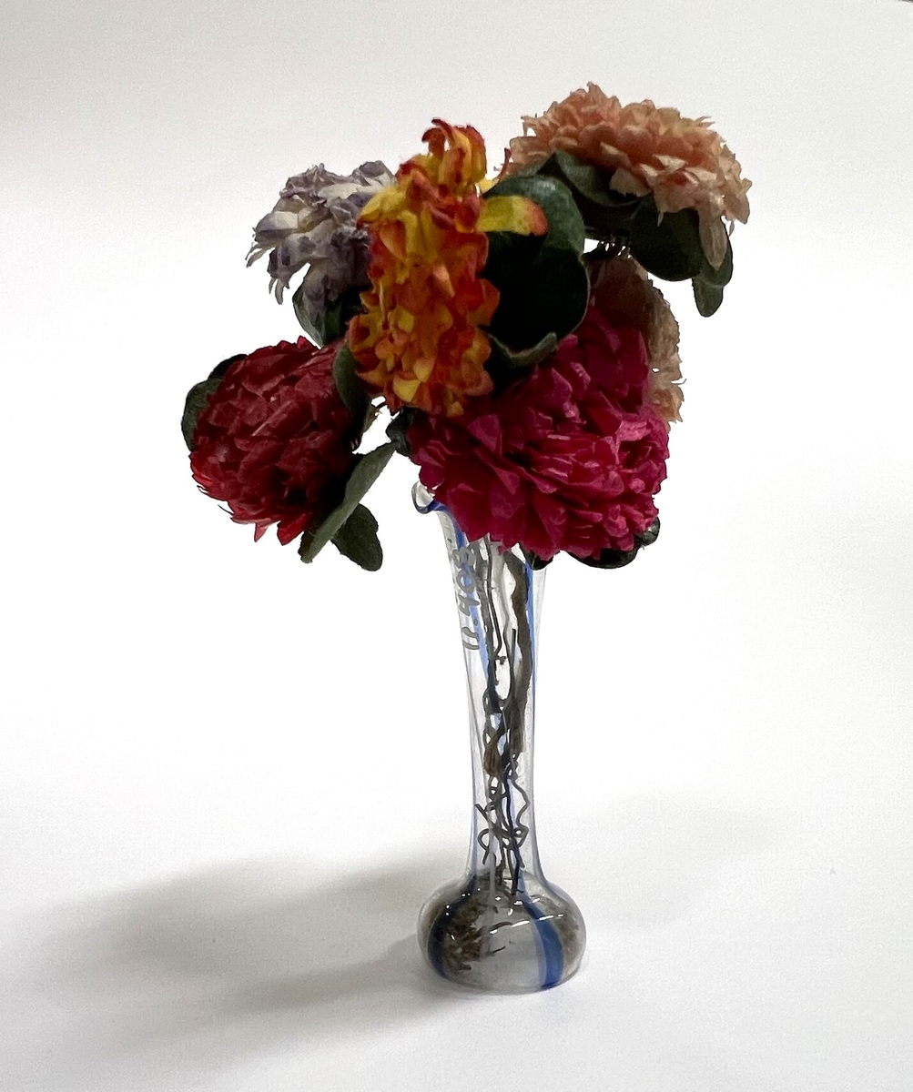 Glasvas med blå ränder. Pappersblommor i rosa, lila, gult och grönt.