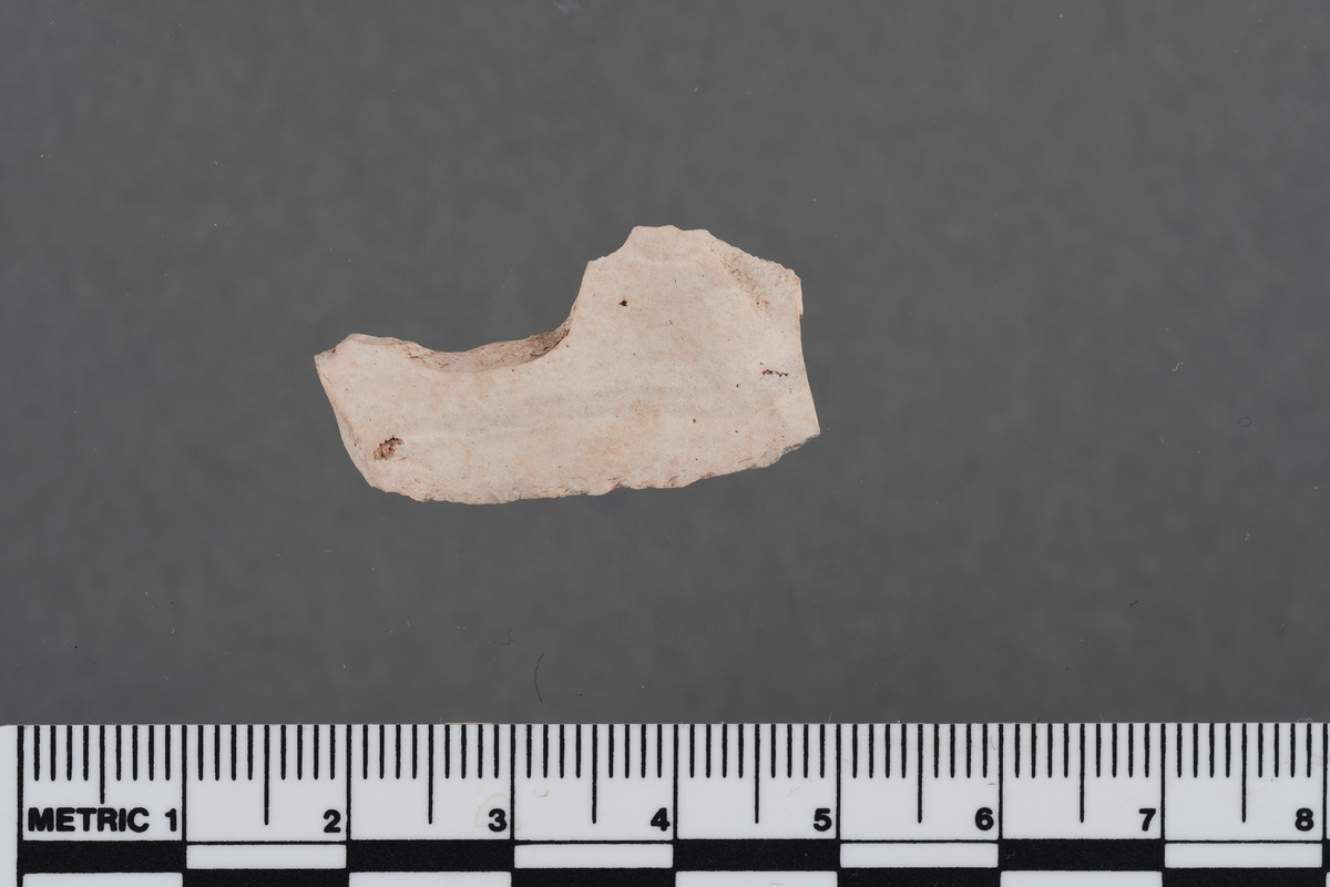 Flekkefragment med rett, svært fin, steil ensidig retusj på venstre sidekant, forside; høyre sidekant er avbrukket; av ryolitt. L. 30 mm, b. 16 mm, t. 3 mm. 200,50x/200,01y, lag 2.