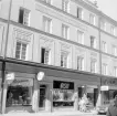 Den från Stockholm verksamme arkitekten Björn Hedvall har ritat en mängd vackra hus i Linköping. Hans avtryck spänner över 50 år, från 1912 till 1961. År 1928 kunde Linköpingsborna räkna in praktfulla Platensgatan 6. I affärsplanet har en rad butiker passerat. Som nytt och lång tid därefter låg här exempelvis en bilhandel som saluförde Chevrolet. Från en senare tid minns många Sportmagasinet. Foto 1971.