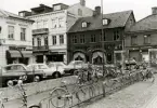 Kvarteret Guldsmeden från Larmtorget. Till vänster kvarteret Blockmakaren. Cyklar vid cykelställ och bilar som är parkerade.