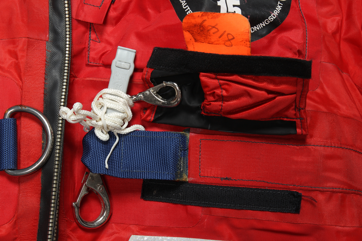 Redningsdrakt i størrelse medium med Stavanger Drilling sin logo på ryggen. 

Drakten er produsert av en flammebestandig neopren-nylonduk og utstyrt med fluorescerende ytterhette med påsydde reflekser. Den har løst innerfôr som er festet til drakten med borrelås. Faste flytemidler er plassert i lommer i fôret.
