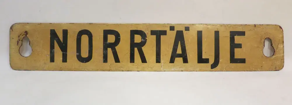 På andra sidan skylten, text Stockholm. Den 28 september 1969 gick sista persontåget från Norrtälje station och under 1970 revs spåren upp mellan Rimbo och Norrtälje.