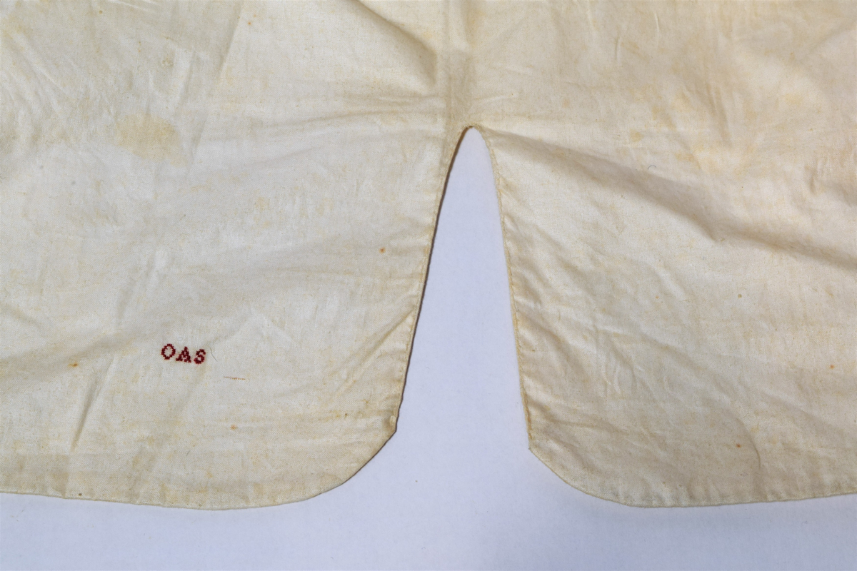 Herrevest i lys beige damask av bomull(?). Sjalskrage med stikning langs kanten. Forstykkene er avrundet nederst og begge har reparasjoner. Lukkes med fire overtrekte knapper. Snittsøm og urlomme på hvert forstykke. Skuldre og rygg er sydd av annet bomullstsoff. I ryggen er det avrundet splitt, spensel med metallspenne. Bomullsfor. På innsiden i ryggen er det små initialer brodert med rød tråd.