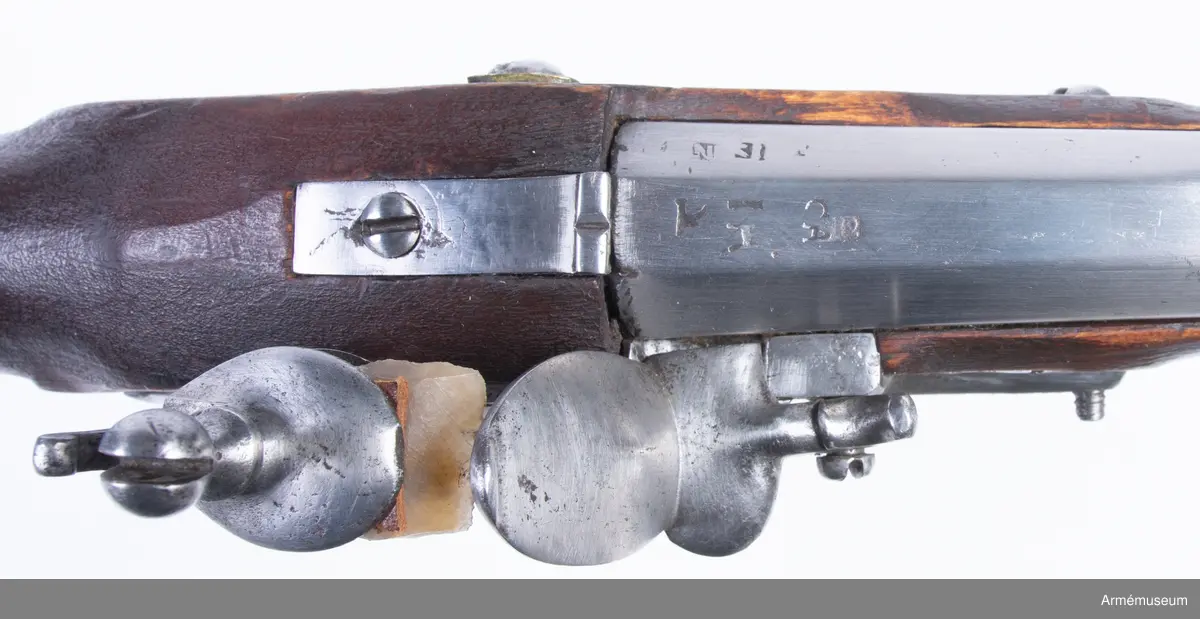 Med flintlås och karbinkolv kallat "karbinpistol" med flintlås. Loppet har 4 refflor. Pipa och lås ursprungligen m/1704. På kammarstycket många otydliga stämplar däribland årtalet 1712. Stämpel på låset med bokstäverna N.B. Beslag av mässing. På undersidan vid varbygelns bakre fot stockmakaremärket P.S.