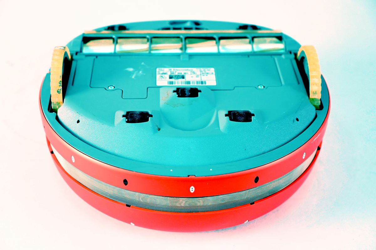 Robotdammsugare typ Trilobite med hölje i röd plast. Dammsugaren navigerar med hjälp av ultraljud. Den återvänder till laddstationen för laddning och stänger av sig själv när dammsugningen är klar.
Märkt "Sample only - not for approval". Typ TR1 ser nr 34700118 model nr ZA1(PS2).