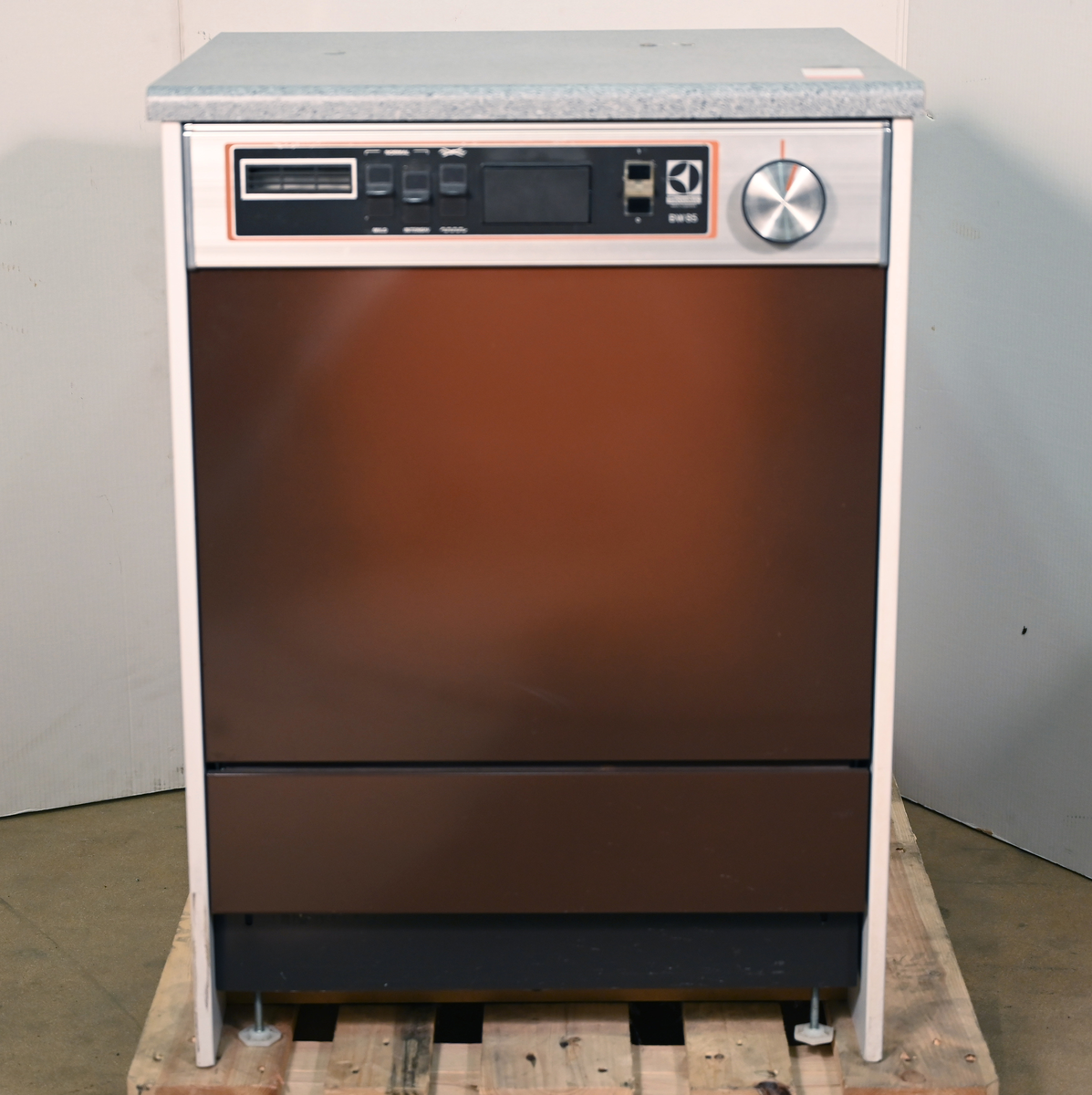 Diskmaskin, skyltexemplar bestående av front till diskmaskin inbyggd i bänkskiva med skåpssidor. Typ BW85, brunt färgtema med aluminiumpanel.