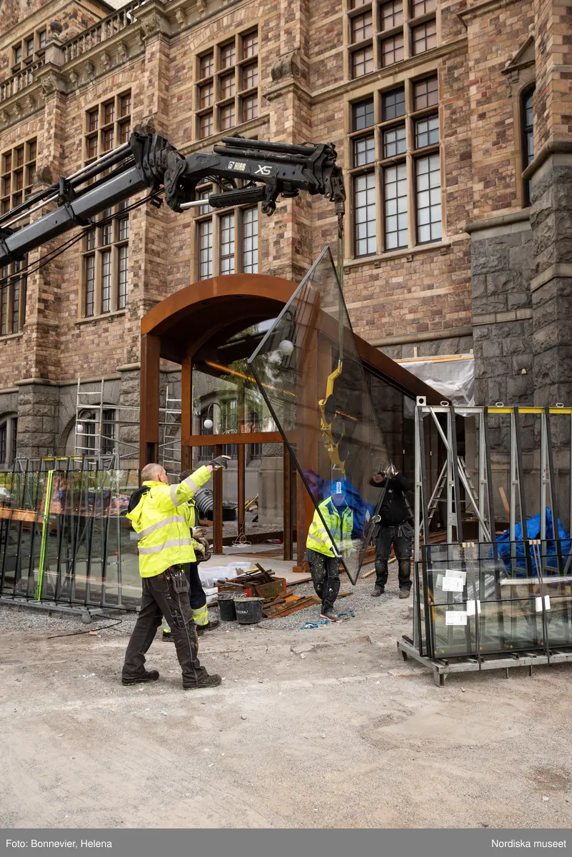 Exteriörer från Nordiska museets västra sida, bakgården, under arbetet med den nya entrén och byggnaden Lusknäppen. Entrén är ritad av Lone-Pia Bach. Konstnären Outi Pieski står för den konstnärliga gestaltningen med konstverket Two Directions, inspirerat av föremål ur museets samiska samlingar. Montering av glaset i utbyggnaden.