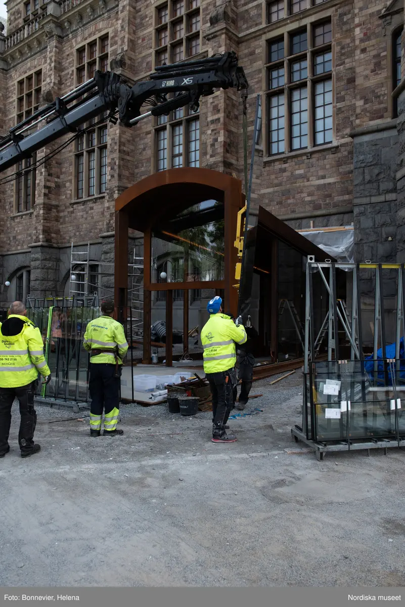 Exteriörer från Nordiska museets västra sida, bakgården, under arbetet med den nya entrén och byggnaden Lusknäppen. Entrén är ritad av Lone-Pia Bach. Konstnären Outi Pieski står för den konstnärliga gestaltningen med konstverket Two Directions, inspirerat av föremål ur museets samiska samlingar. Montering av glaset i utbyggnaden.